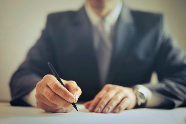 person signing papers in suit