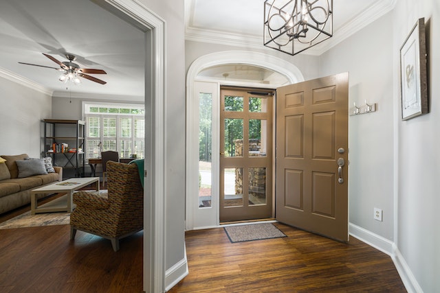 inside of house with mirror showing living room and brown front door